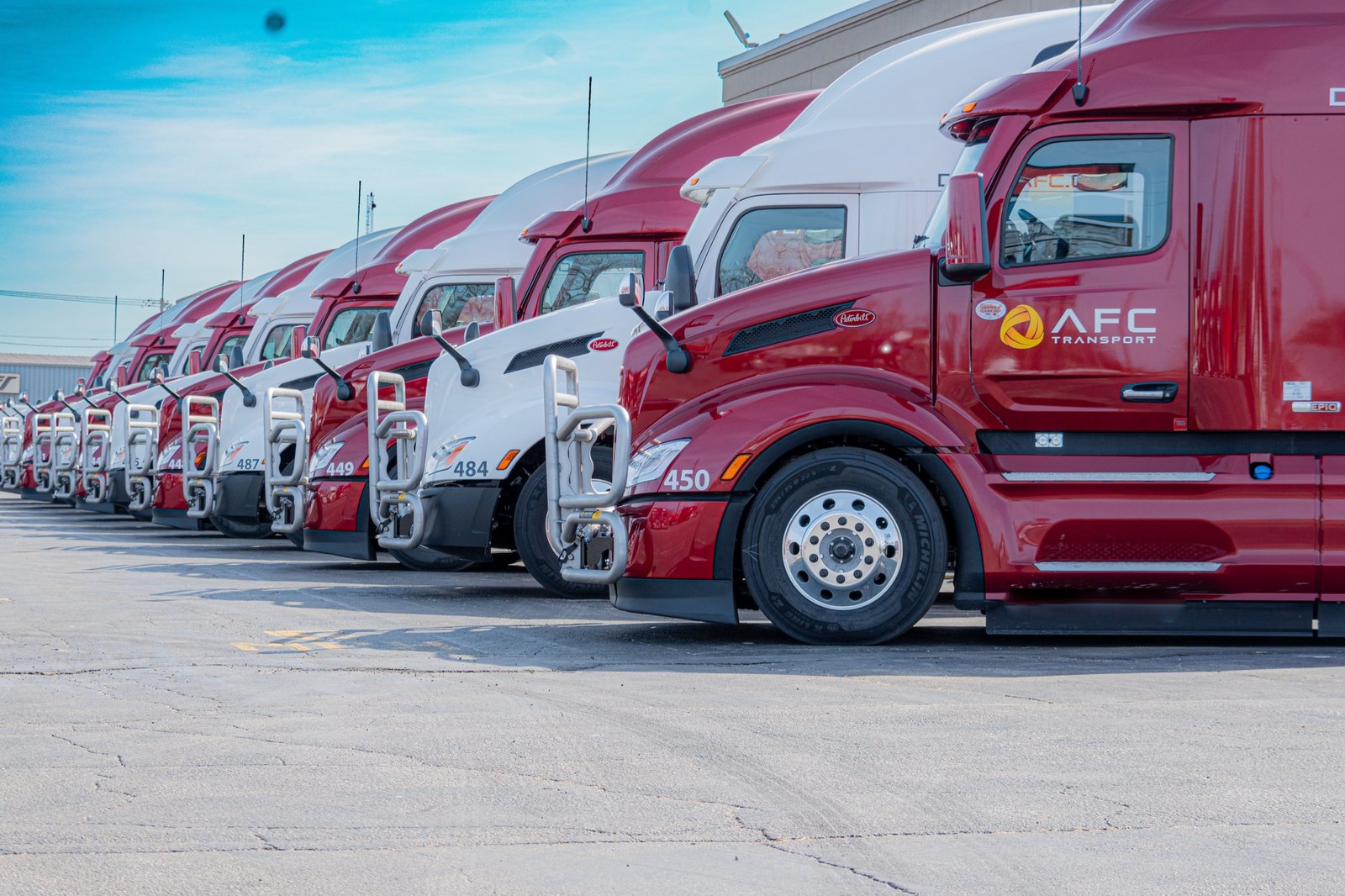 A row of AFC red and white flatbed tractors lined up at the terminal