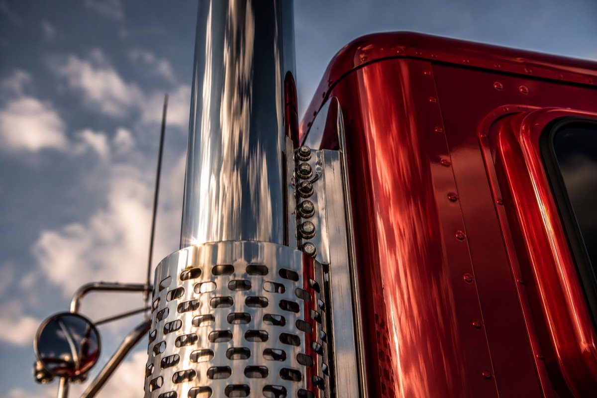Close-up of a polished chrome exhaust and red cab of an AFC tractor